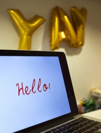 A computer screen saying hello and golden balloons saying yay!.